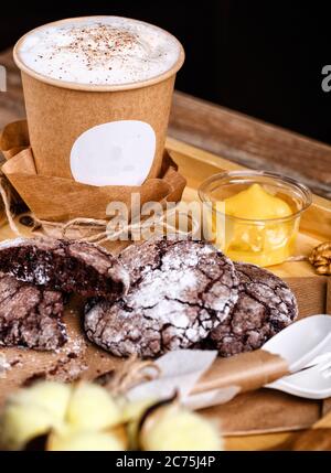 Caffè alla cannella in una tazza di carta con biscotti su un vassoio di legno Foto Stock