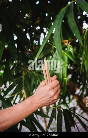 Bambù riutilizzabile beva paglia in mani di uomo su sfondo bambù. Concetto di zero sprechi Foto Stock