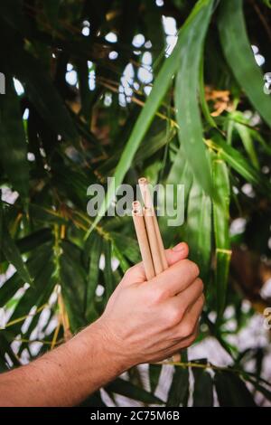 Bambù riutilizzabile beva paglia in mani di uomo su sfondo bambù. Concetto di zero sprechi Foto Stock