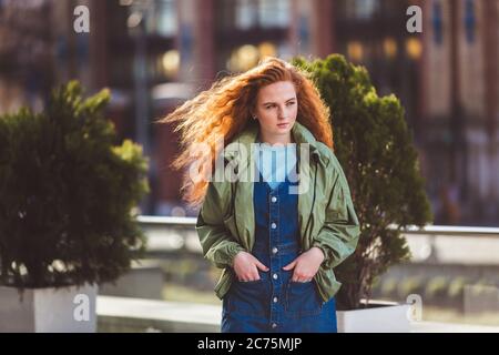 Ritratto di giovane ragazza bella rossa che cammina per la strada della grande città Foto Stock