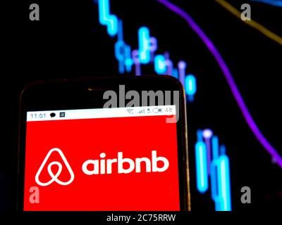 In questa illustrazione fotografica il logo Airbnb viene visualizzato su uno smartphone sullo sfondo di un grafico con curve in discesa. Secondo i rapporti internazionali dei mezzi di comunicazione durante l'epidemia di coronavirus COVID-2019 il fondatore di Airbnb ha detto che a causa della pandemia, 12 anni di sforzo sono stati distrutti in 6 settimane. Foto Stock