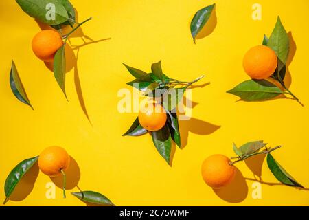 Arance intere con foglie di arance su sfondo giallo Foto Stock