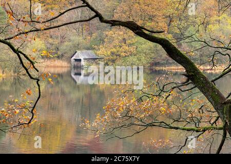 Il Boathouse su Rydal acqua è incorniciato da fogliame di autunno e riflessa nelle calme acque del lago su di una tranquilla mattina autunnale nei laghi. Foto Stock