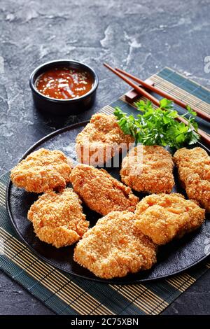 HireKatsu, cotolette di maiale giapponesi su un piatto nero con deliziosa salsa al miso aromatizzante su un tappetino di bambù, vista verticale dall'alto Foto Stock