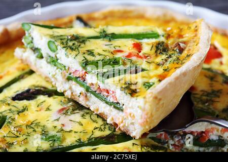 primo piano di quiche con asparagi di salmone ripieno tagliato a fette in una teglia, vista orizzontale dall'alto Foto Stock