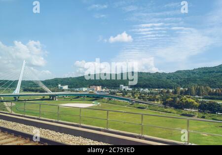 Vista dalla finestra del treno sul moderno ponte automobilistico e alcuni edifici nella zona rurale della corea del Sud Foto Stock