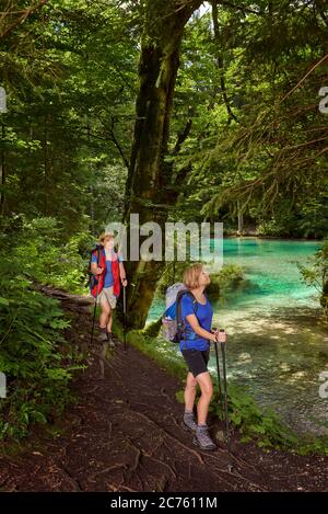 Due donne di mezza età camminano lungo la riva di un lago di montagna e godono della vista. Foto Stock