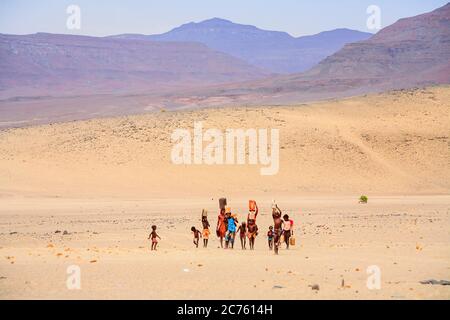 Himba donna e bambini che lavorano portando acqua ad un villaggio di Himba persone della tribù indigene della regione di Kunene, Namibia settentrionale, Africa sudoccidentale Foto Stock