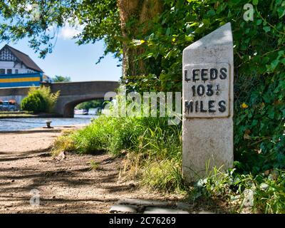 Focus su un indicatore di distanza a Burscough sul canale Leeds-Liverpool nel Lancashire nel Regno Unito. Burscough Bridge appare sullo sfondo. Foto Stock