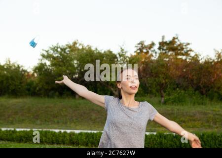 Giovane donna toglie la maschera medica in piedi all'aperto. Foto Stock