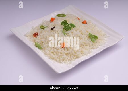 Il Pulav o Pulao, ottenuto con riso basmathi, verdure e spezie indiane, è stato sistemato in una tavola quadrata bianca con fondo bianco o testu Foto Stock