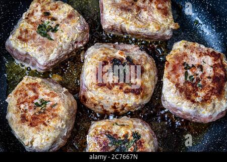 Cotolette di maiale, riscaldate in padella nera in ceramica con olio vegetale. Il processo di frittura delle bistecche. Cucina tradizionale. Foto Stock