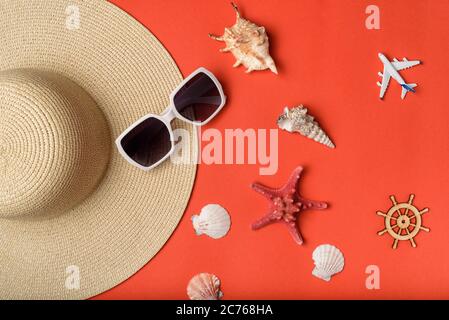 Occhiali da sole, conchiglie, aereo, parte di un cappello e volante. Sfondo corallo vivo. Disposizione piatta. Concetto di viaggio Foto Stock