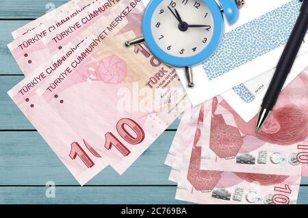 10 lire turche e sveglia con penna e buste. Concetto di stagione fiscale, termine di pagamento per credito o prestito. Operazioni finanziarie con pos Foto Stock