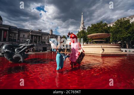 Londra / UK - 07/11/2020: Coppia che indossa costumi e che tiene banner in piedi nella fontana dopo che il gruppo di diritti animali gira fontane rosso in Foto Stock