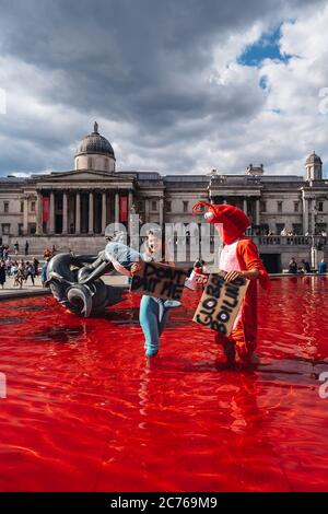 Londra / UK - 07/11/2020: Coppia che indossa costumi e che tiene banner in piedi nella fontana dopo che il gruppo di diritti animali gira fontane rosso in Foto Stock