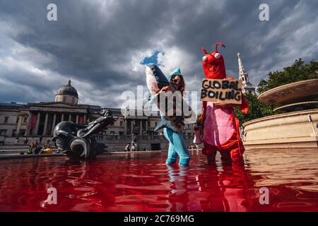 Londra / UK - 07/11/2020: Coppia che indossa costumi e che tiene banner in piedi nella fontana dopo che il gruppo di diritti animali gira fontane rosso in Foto Stock