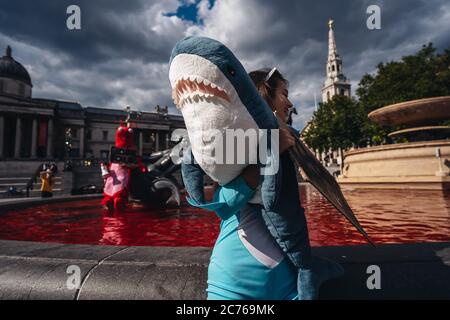 Londra / UK - 07/11/2020: Coppia che indossa costumi e che tiene banner in piedi nella fontana dopo che il gruppo di diritti animali gira fontane rosso in Foto Stock