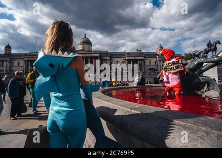 Londra / UK - 07/11/2020: Coppia che indossa costumi e che tiene banner in piedi nella fontana dopo che il gruppo di diritti animali gira fontane rosso in Foto Stock