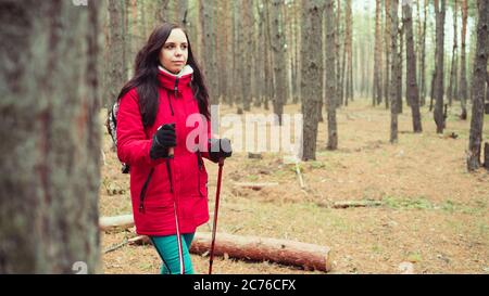 Una giovane donna è impegnata nel nordic walking in boschi. Foto Stock