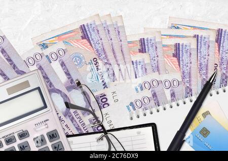 100 bollette e calcolatrice per piso filippino con occhiali e penna. Concetto di stagione di pagamento fiscale o soluzioni di investimento. Pianificazione finanziaria o contabile pa Foto Stock
