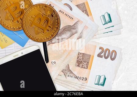 200 bollette ceche e monete d'oro con smartphone e carte di credito. Concetto di investimento in criptovaluta. Crypto mining o transazioni commerciali Foto Stock