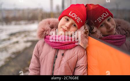 Ritratto di affascinante bambina, in posa vicino al trasporto. Bambino in abiti casual a piedi nella stagione invernale. Foto Stock