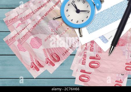 10 lire turche e sveglia con penna e buste. Concetto di stagione fiscale, termine di pagamento per credito o prestito. Operazioni finanziarie con pos Foto Stock