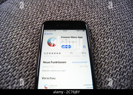 Corona WARN App del Governo Federale Tedesco nell'Apple App Store su uno smartphone che gioiva su sfondo tessile. Foto Stock