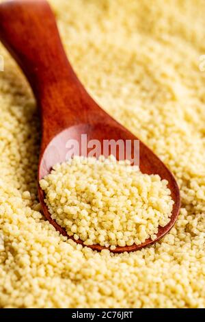 Asciugare il couscous giallo in un cucchiaio di legno. Foto Stock