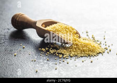 Couscous giallo secco in paletta di legno. Foto Stock