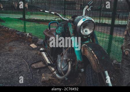 Stary Oskol, Russia 25 gennaio 2019: Vecchio motociclo arrugginito vicino recinzione a terra. Primo piano di una moto rotta abbandonata. Foto Stock