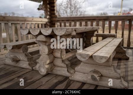 Tavolo in legno con panchine nel parco divertimenti. Terrazza recintata con tavolo e panchine in un parco vuoto durante la cupa giornata autunnale Foto Stock