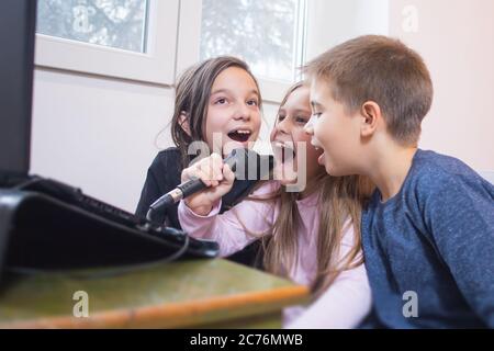 tre bambini che cantano il karaoke insieme Foto Stock