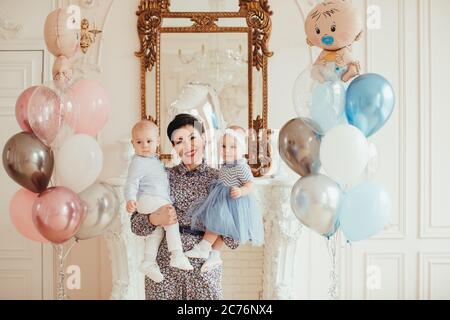 Ritratto di una donna sorridente che tiene i suoi nipoti gemelli il loro 1 ° compleanno Foto Stock