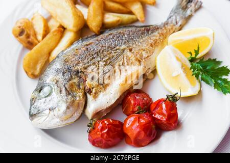 La frittura di pesce dorado con patate chips, erbe fresche e limone Foto Stock