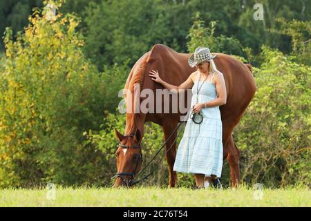 Ritratto di una bella giovane allegra donna con un cavallo all'aperto. Measow in estate Foto Stock