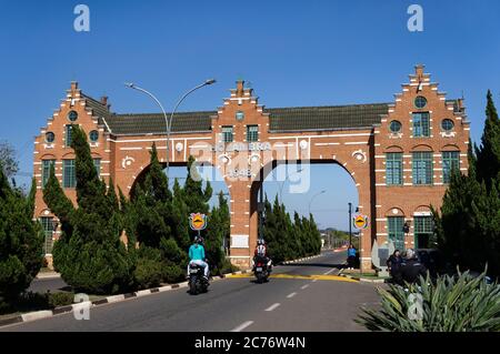 Motociclisti passando per la facciata in mattoni d'ingresso della porta della città di Holambra con la sua tipica architettura olandese situata in via Rota dos Imigrantes. Foto Stock