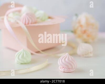 Sfondo romantico pastello con piccole meringhe in una scatola, fiore e nastri. Foto Stock