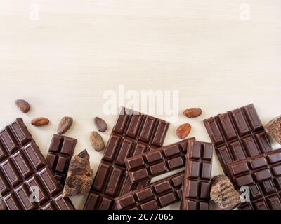Barrette di cioccolato, fagioli di сhocolate, pezzi di cioccolato sparsi su uno sfondo chiaro Foto Stock
