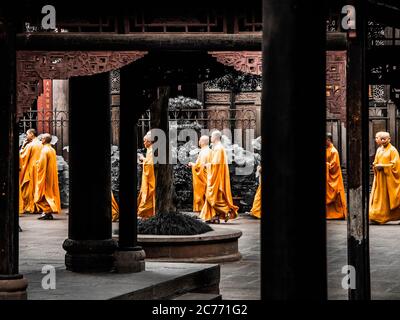 CHENGDU, CINA - 27 AGOSTO 2012: Monaci buddisti in orange passeggiate tra le colonne del monastero di Wenshu a Chengdu, Cina. Foto Stock