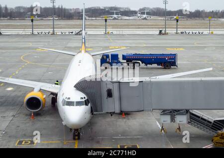 aereo con ponte a getto collegato, serbatoio di gas blu con parola infiammabile trasporta il carburante all'aereo. aereo in parcheggio. vista pista. Foto Stock