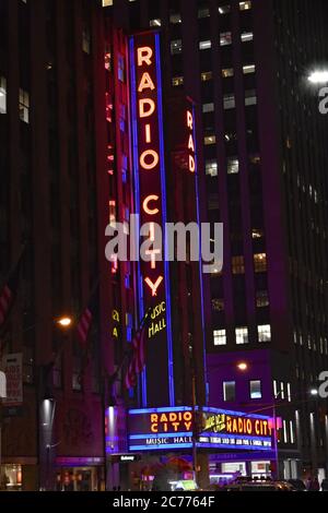 Il marchese art deco con luci al neon si illuminano di notte sulla radio City Music Hall vista dal sesto viale di New York City. Foto Stock