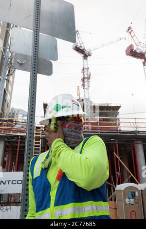 Austin, Texas USA 14 luglio 2020: I lavoratori del settore edile ascoltano le informazioni sulla sicurezza mentre si preparano per un turno di otto ore nel calore a 105 gradi del Texas. Gli equipaggi sono al secondo piano di un edificio a 53 piani, mentre prendono precauzioni contro la pandemia del coronavirus. Foto Stock