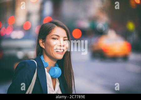 Donna asiatica che usa le cuffie che cammina sulla città di New York, il lavoro di strada si sposti nel tramonto del pomeriggio. Felice sorridente multirazziale caucasico cinese giovane Foto Stock