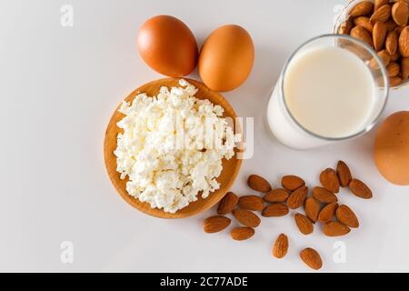 Un insieme di alimenti proteici sani per una dieta equilibrata. Ricotta formaggio, uova e noci su sfondo bianco. Foto Stock