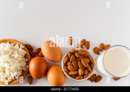 Un insieme di alimenti proteici sani per una dieta equilibrata. Ricotta formaggio, uova e noci su sfondo bianco. Foto Stock