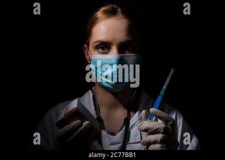 Medico femminile con maschera contenente il vaccino e pillole in mano, vaccino coronavirus, covid-19 cura Foto Stock