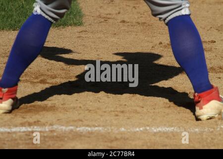 Un primo baseman di baseball getta un'ombra mentre copre la base per un gioco di decapaggio. Foto Stock