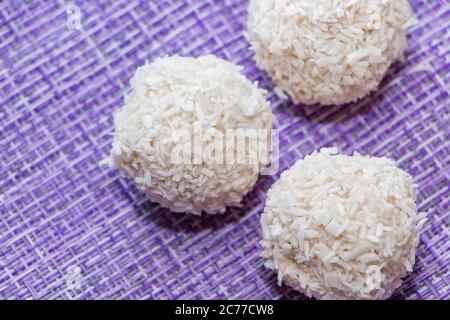 Caramelle fatte in casa al cocco su sfondo viola da vicino Foto Stock